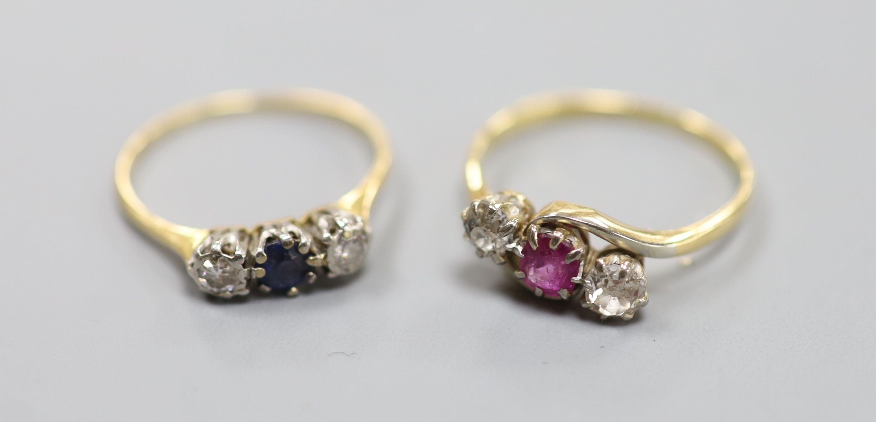 An 18ct & Plat, sapphire and diamond three stone ring, size O/P, gross 2.1 grams and a yellow metal, ruby and diamond three stone crossover ring, size Q, gross 3 grams.